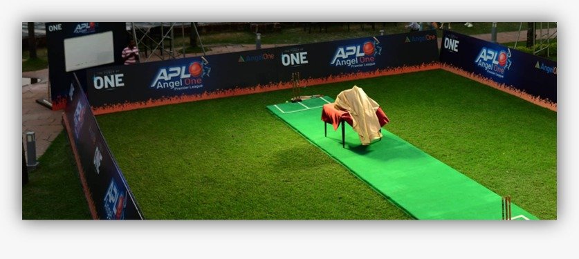 Branded outdoor cricket event setup with artificial turf, cricket pitch and sponsor panels